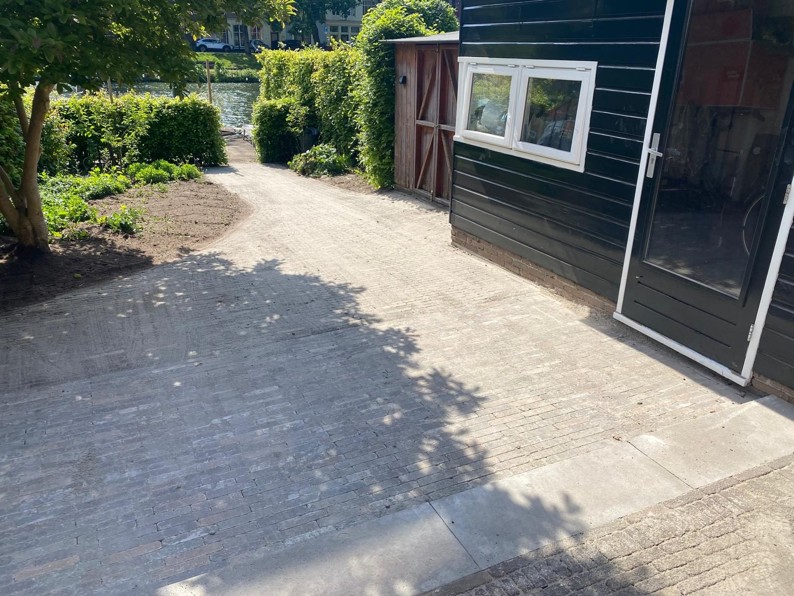 Nieuw klinkerpad langs een groen tuinhuis